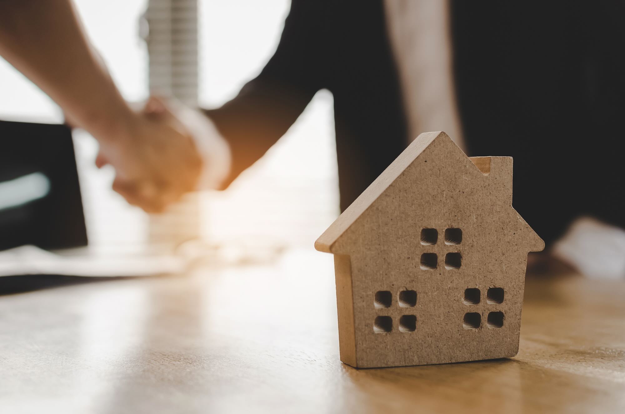 real estate broker manager hand shake to customer after signing contract for buying house in estate agent office behind House model, investment, home loan contract, buy and sell house concept Tax bill